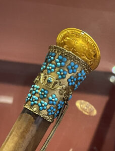 A wooden cane encrusted with turquoise stones and with a gold top